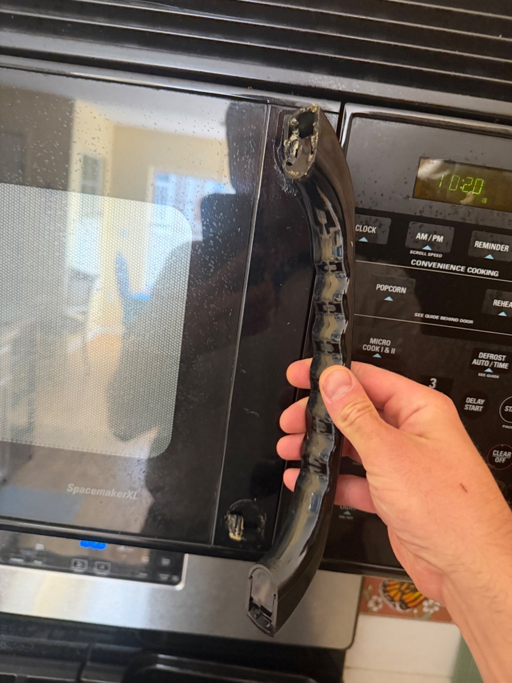 Broken over-the-range microwave door handle during a Denver microwave repair assessment