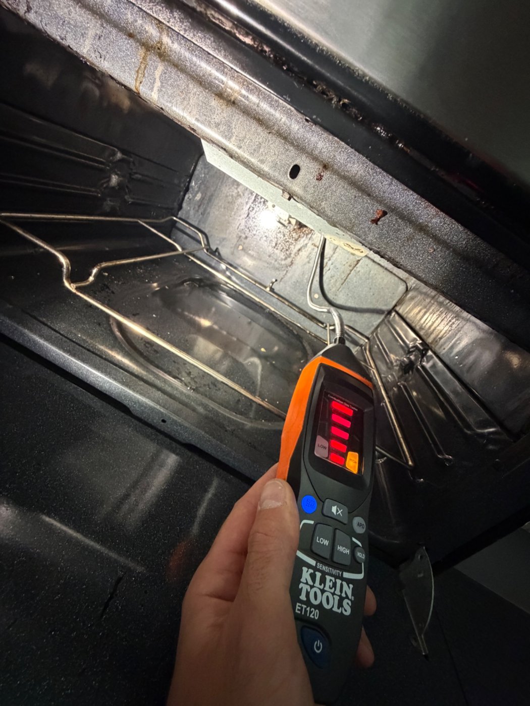Electronic gas leak detector being used inside an oven during a Denver range repair